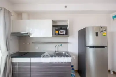Modern kitchen with sleek cabinets, stainless steel fridge, and built-in microwave in a stylish apartment.