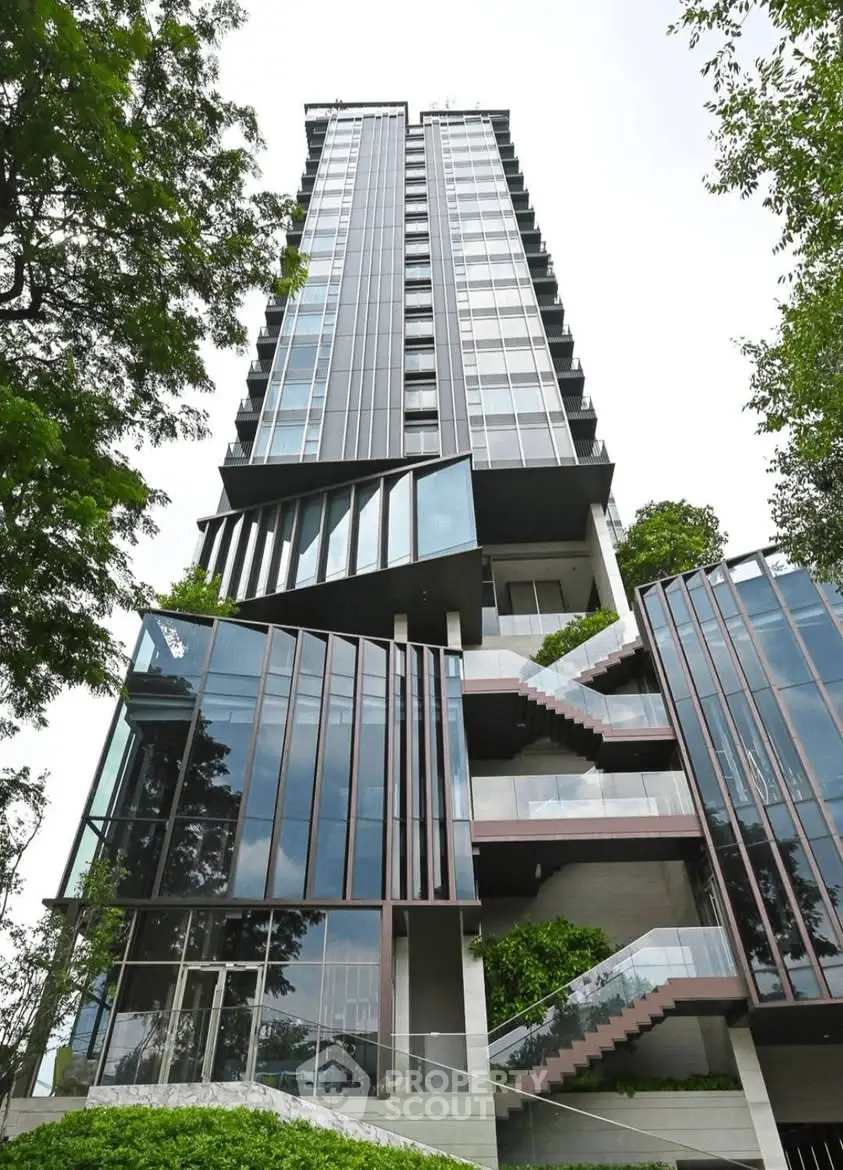 Modern high-rise building with sleek glass facade and lush greenery