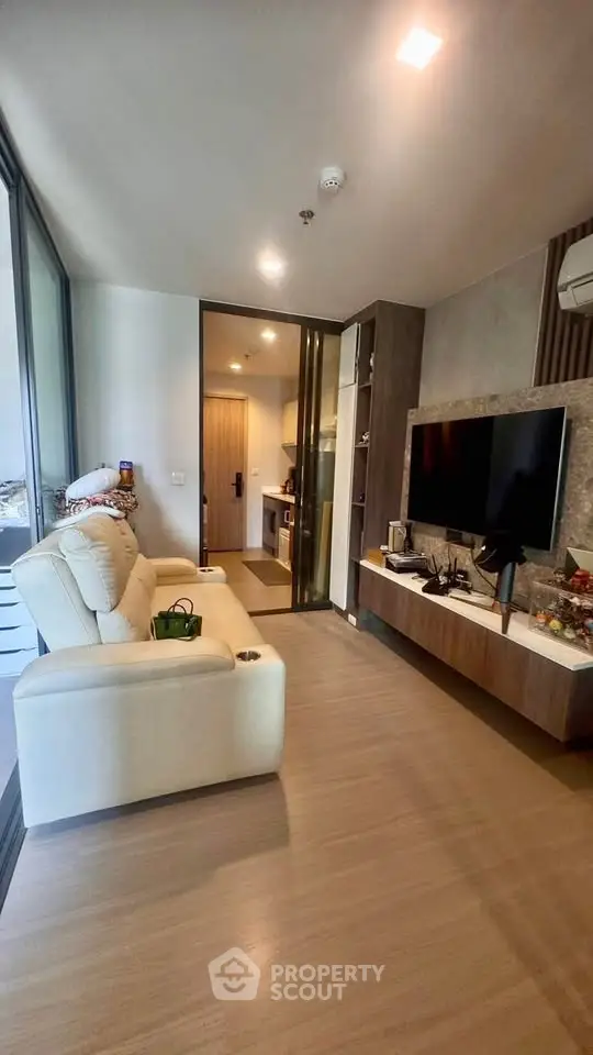 Modern living room with sleek TV setup and cozy seating in a stylish apartment.