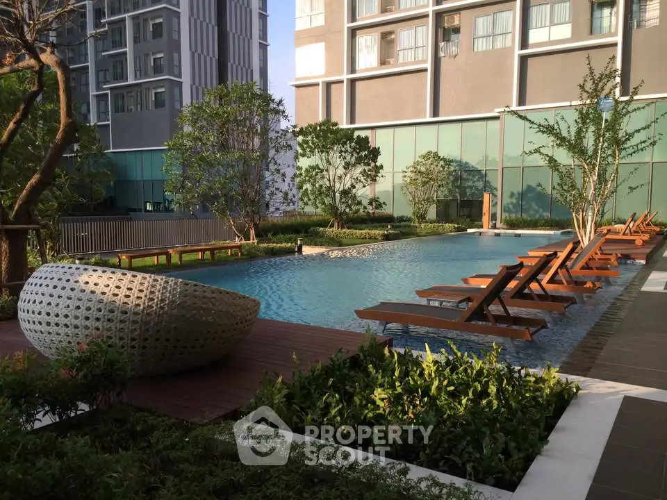 Luxurious residential pool area with modern sun loungers and lush greenery.