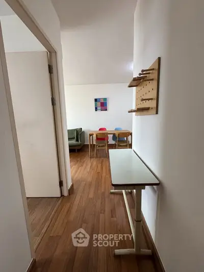 Charming interior hallway leading to a cozy living area with modern decor and wooden flooring.