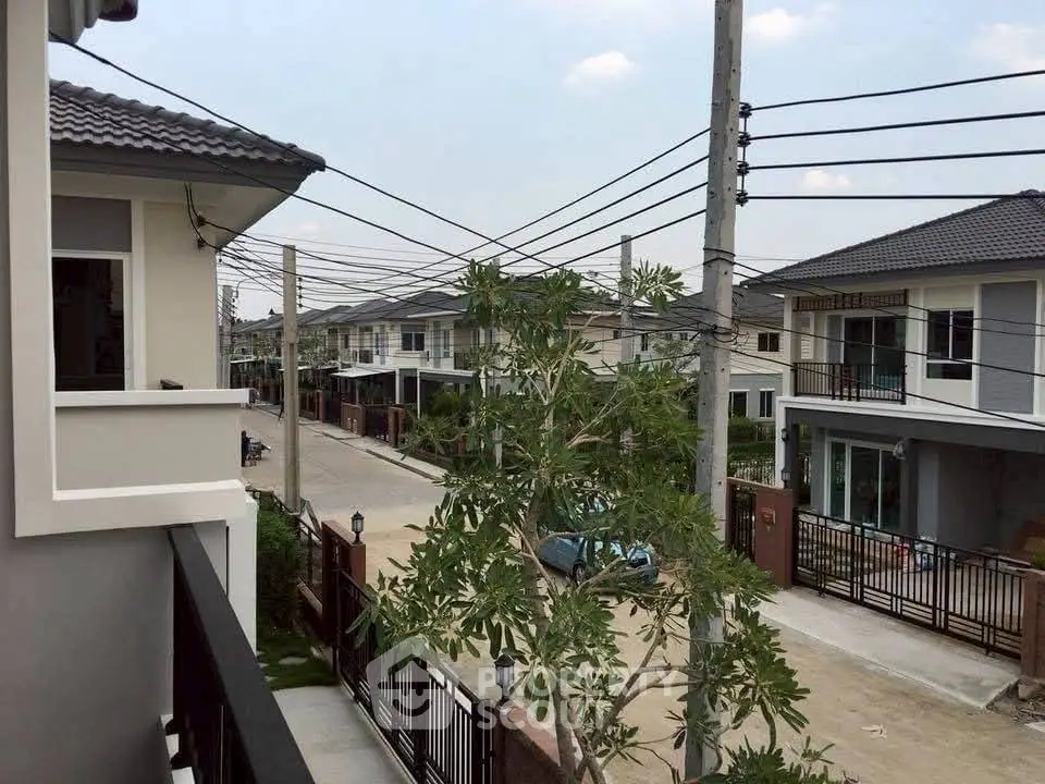 Charming suburban neighborhood view from balcony with modern houses and lush greenery.