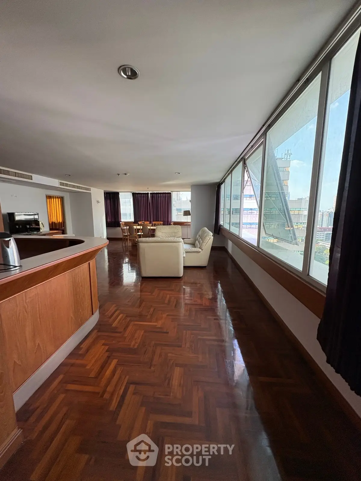 Spacious living room with large windows and wooden flooring, offering a bright and inviting atmosphere.