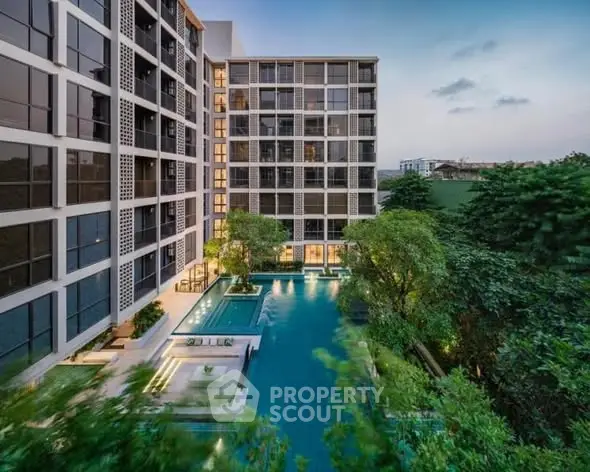 Modern apartment complex with stunning pool and lush greenery.