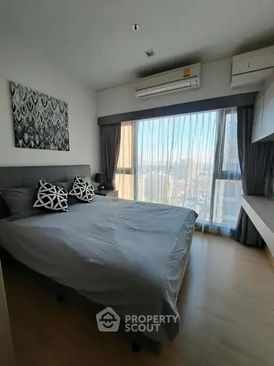 Modern bedroom with large windows and city view, featuring stylish decor and ample natural light.