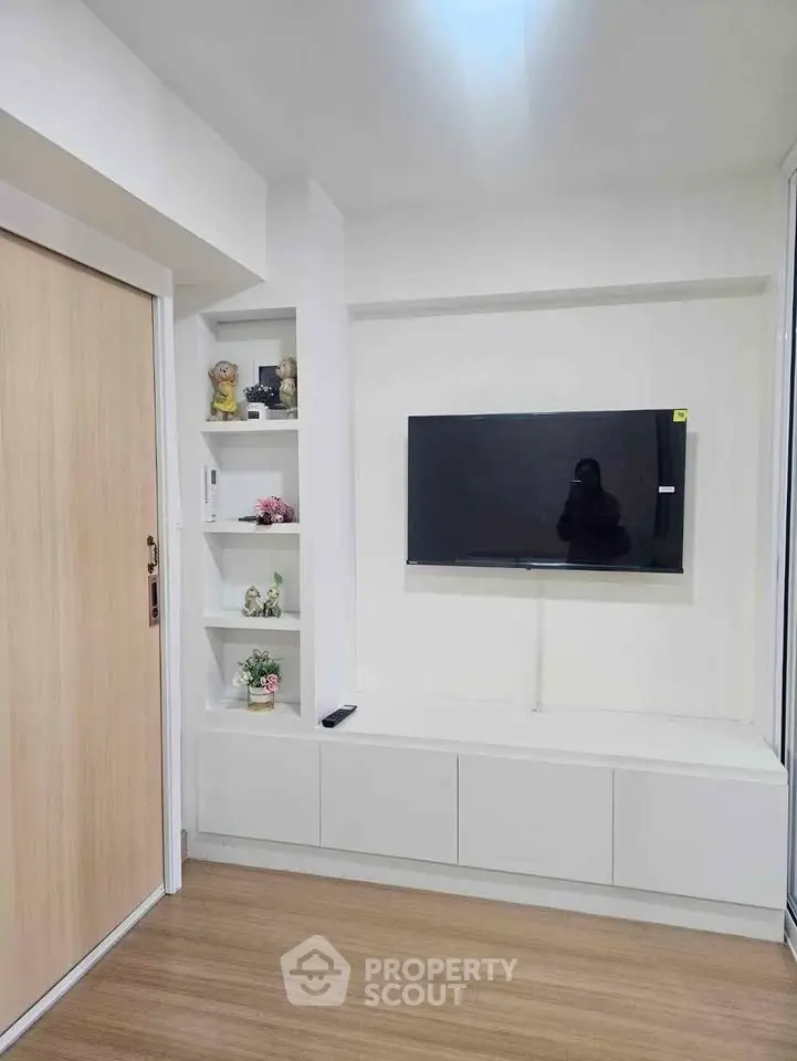 Modern living room with wall-mounted TV and built-in shelves, featuring sleek design and wooden flooring.