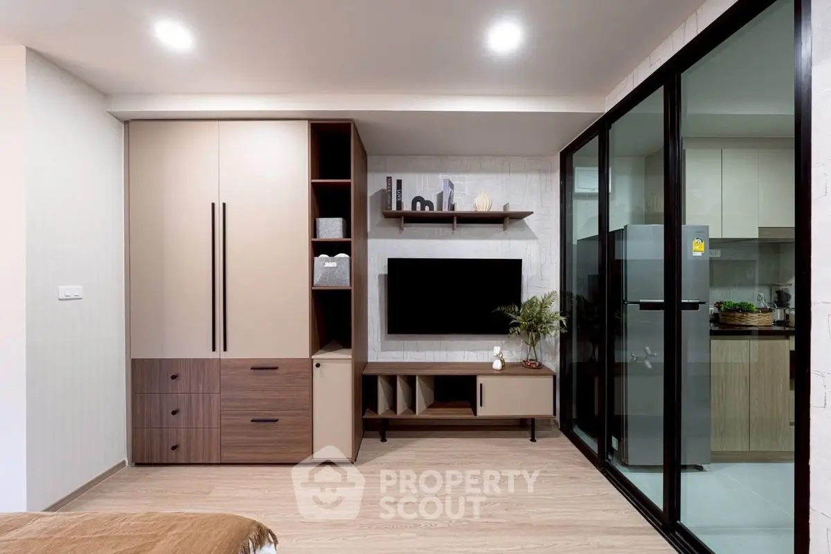 Modern living room with sleek storage and glass partition to kitchen