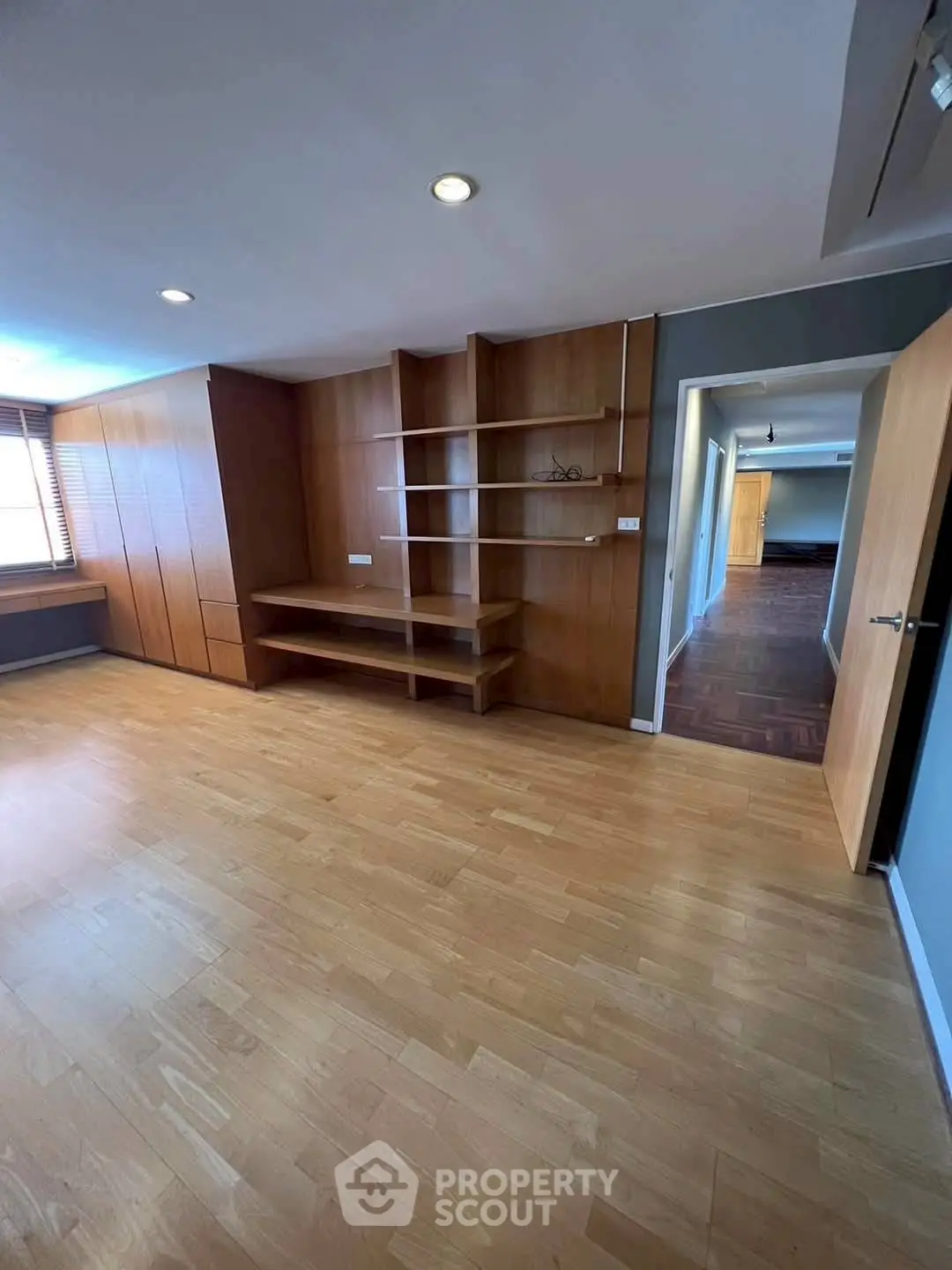 Spacious study room with wooden flooring and built-in shelves, perfect for a home office setup.