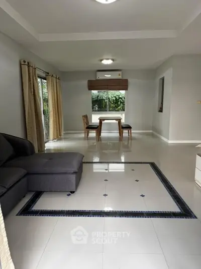 Spacious living room with modern decor and dining area, featuring large windows and elegant tile flooring.