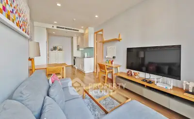 Modern living room with cozy sofa, large TV, and open kitchen layout
