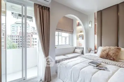 Luxurious bedroom with cozy reading nook and balcony view in modern apartment.