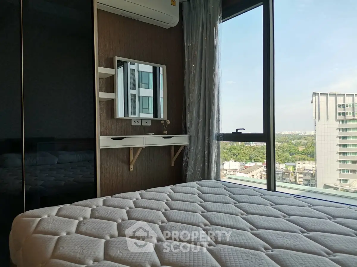 Modern bedroom with large window offering stunning city view, featuring sleek furniture and air conditioning.