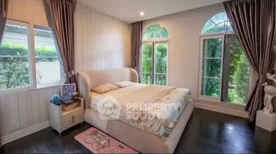 Luxurious bedroom with elegant decor and large windows offering garden views.
