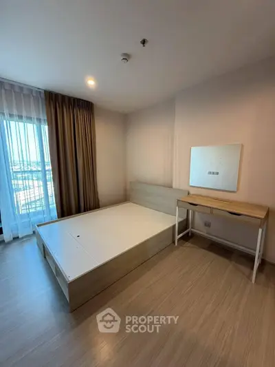 Spacious bedroom with modern furnishings and large window offering natural light.