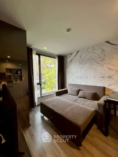 Modern living room with stylish sofa and large window offering natural light and outdoor view.