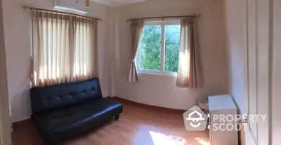 Cozy living room with black sofa and large window offering natural light