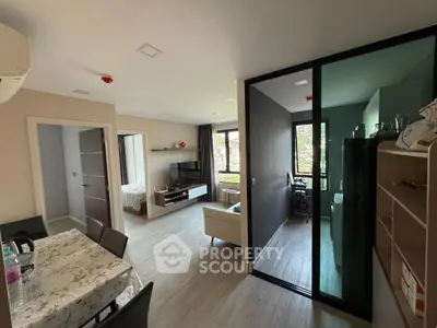 Modern open-plan living room with dining area and glass partition, featuring stylish decor and natural light.