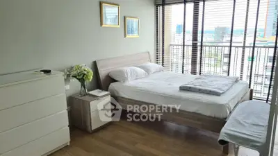 Modern bedroom with city view, featuring sleek furniture and large windows for natural light.