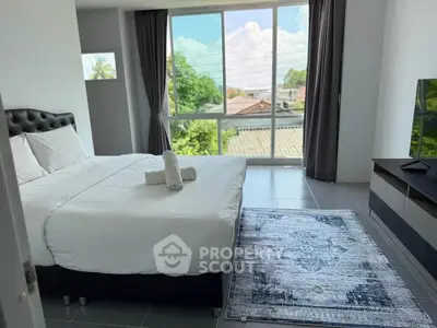 Spacious bedroom with large window offering a serene view, modern decor, and cozy ambiance.