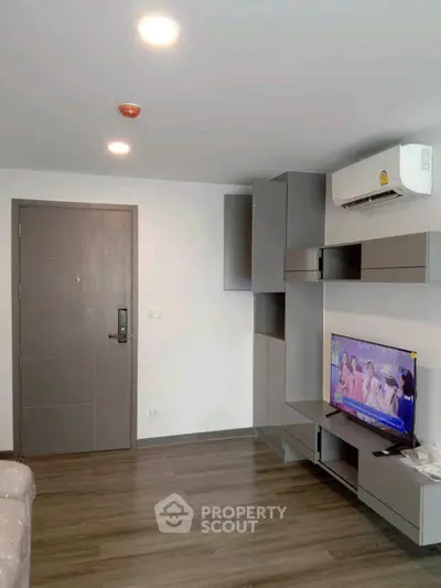 Modern living room with sleek gray furniture and wall-mounted TV in a stylish apartment.