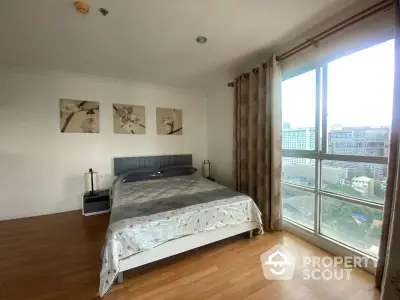 Spacious bedroom with large window offering stunning city view in modern apartment.