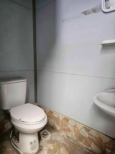Compact bathroom with tiled floor and basic fixtures, ideal for small spaces.
