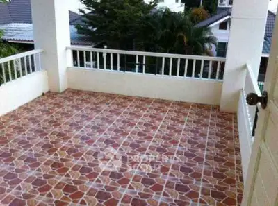 Spacious tiled balcony with railing and scenic view of surrounding greenery.
