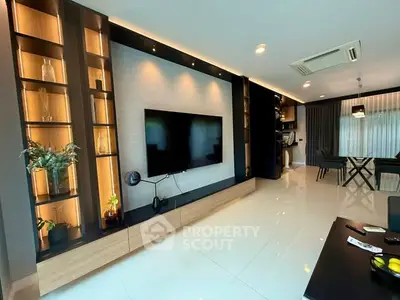Modern living room with sleek design and large TV, open layout to dining area.