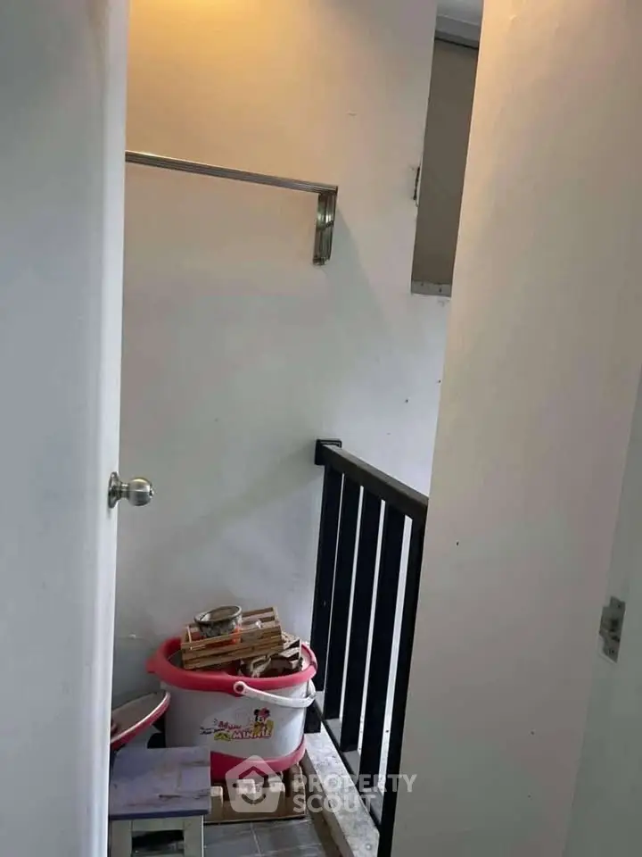 Compact storage area with railing and cleaning supplies, ideal for small spaces.