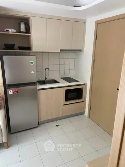 Modern compact kitchen with sleek cabinetry and built-in appliances in a cozy apartment.