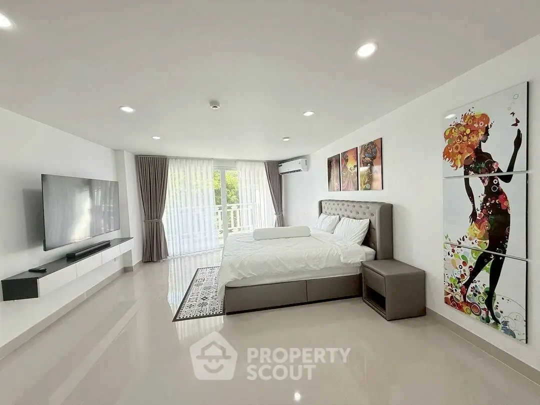 Spacious modern bedroom with elegant decor and large windows for natural light.