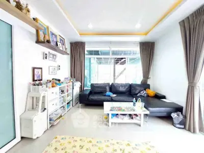 Spacious living room with modern black sofa and large windows