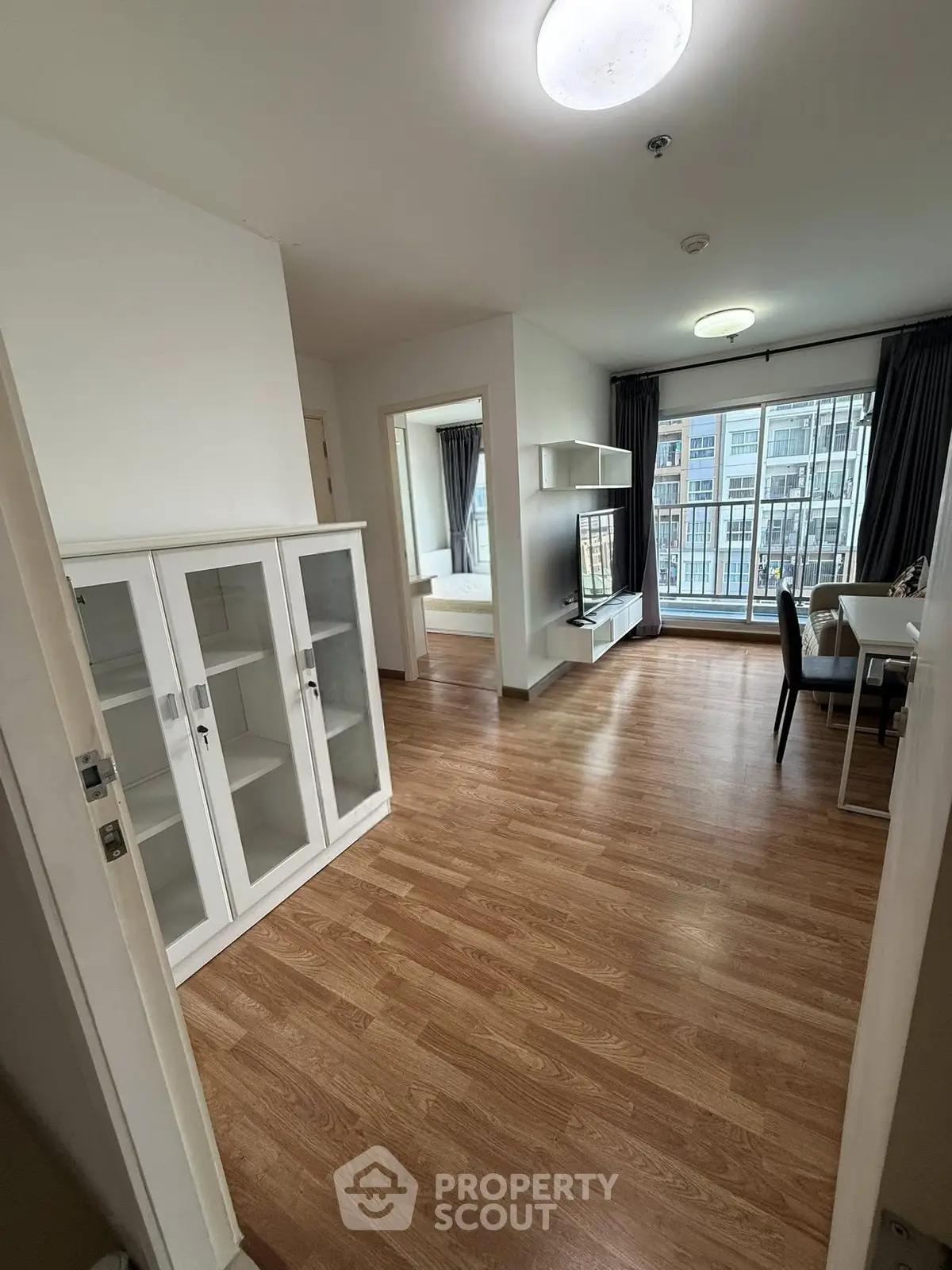 Modern apartment interior with open living area and large windows offering natural light.