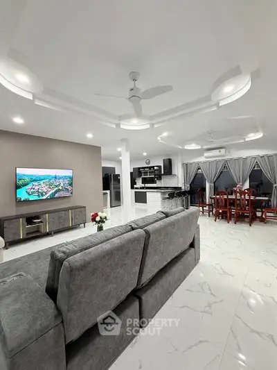 Spacious modern living room with open kitchen and elegant dining area, featuring sleek furniture and stylish decor.
