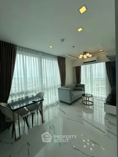 Modern living room with marble flooring and large windows offering natural light.