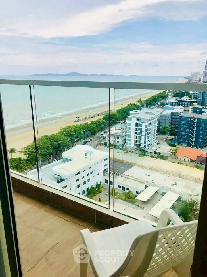 Stunning beachfront balcony view with glass railing overlooking ocean and cityscape.