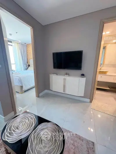 Modern apartment interior with sleek TV setup and glimpse of bedroom and bathroom.