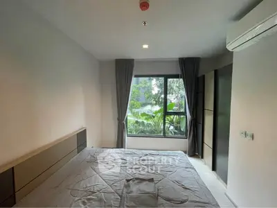 Modern bedroom with large window and garden view, featuring sleek design and air conditioning.