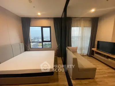 Modern studio apartment with large windows and city view, featuring a cozy living area and sleek furnishings.