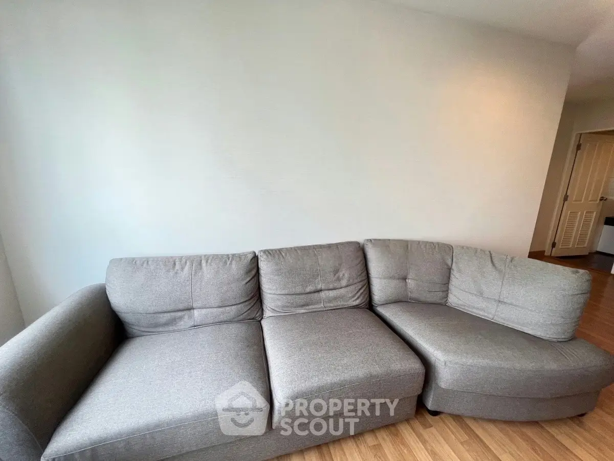 Spacious living room with modern gray sectional sofa and wooden flooring