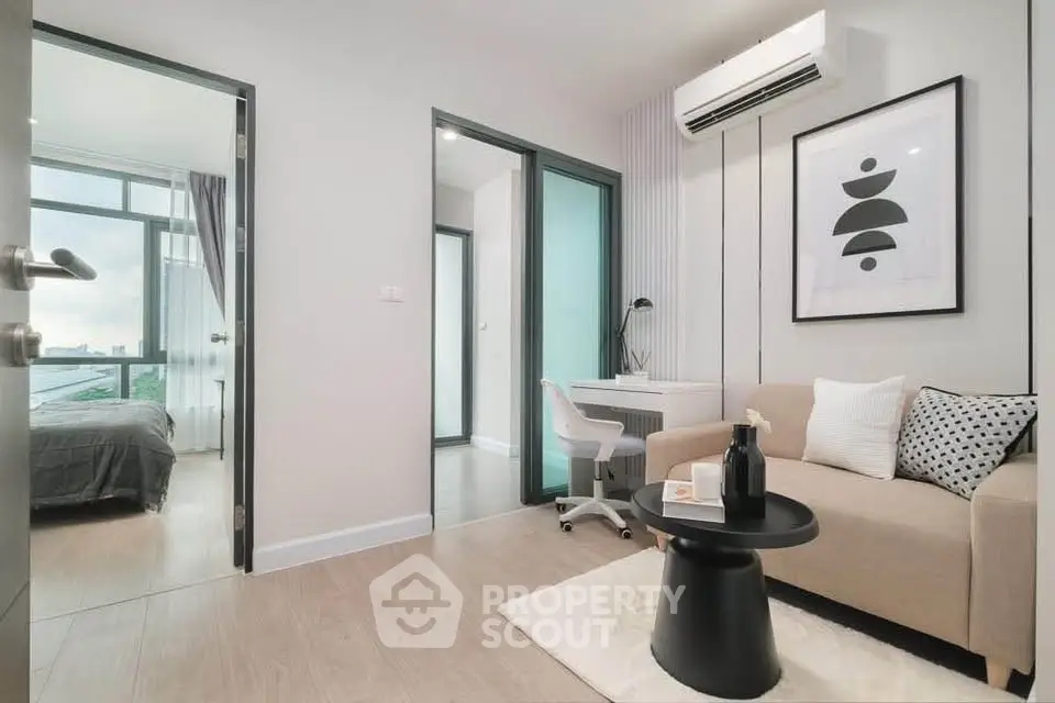 Modern living room with stylish decor and natural light, featuring a cozy sofa and a sleek workspace.