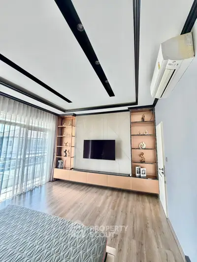 Modern bedroom with sleek design, large window, and built-in entertainment unit.