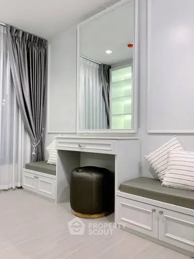 Elegant bedroom corner with vanity and seating, featuring modern decor and ample natural light.