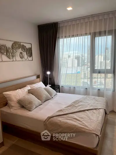 Modern bedroom with city view, featuring elegant decor and natural light through large windows.