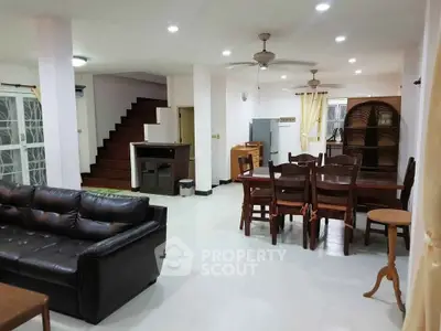 Spacious open-plan living and dining area with modern furnishings and staircase.