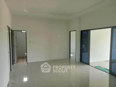 Spacious empty room with tiled flooring and sliding glass doors leading to a balcony.