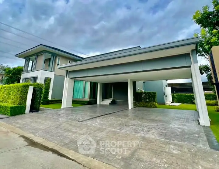 Modern two-story house with spacious driveway and lush green surroundings.