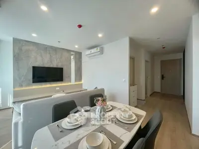 Modern open-plan living room with dining area, featuring sleek furniture and contemporary design.