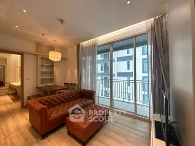 Modern living room with leather sofa and large windows leading to a balcony.