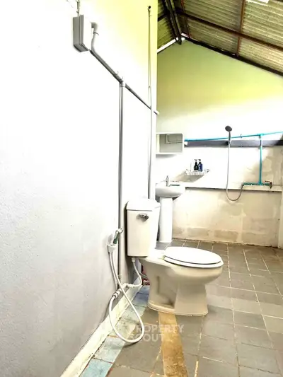 Spacious bathroom with modern fixtures and natural lighting, featuring a toilet and sink.